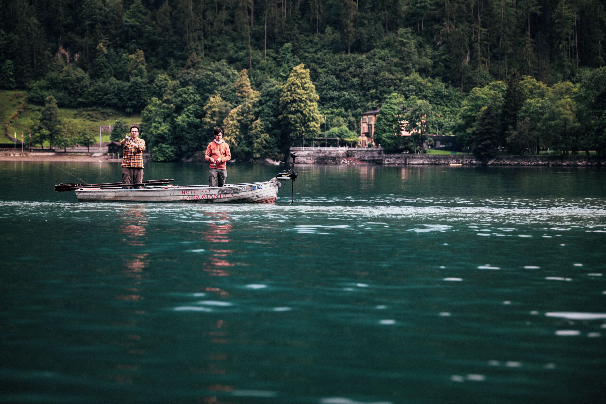 A boat on a lake with two people fishing.