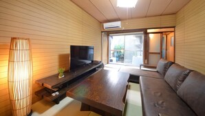 A modern living room with a flat-screen TV, wooden flooring, a sofa, and a sliding glass door leading to a balcony. - Kyoto House (Kyoto)