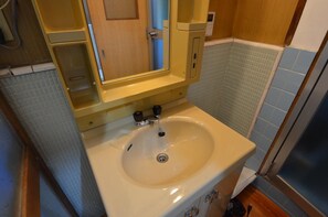 A bathroom with a beige sink, a mirror, and a wooden door. - Kyoto House (Kyoto)