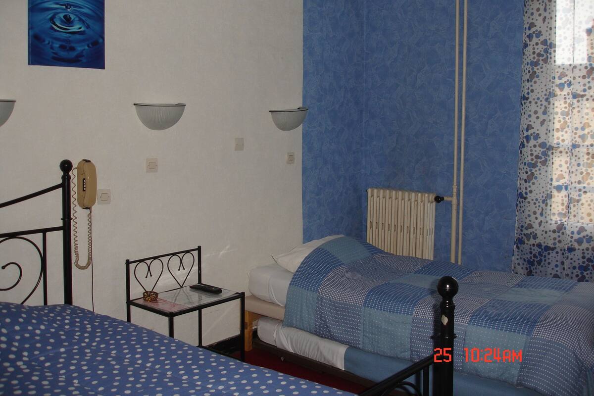 Ein Schlafzimmer mit zwei Betten, einem Nachttisch, einem Telefon und einer Heizung.