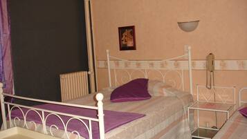 A single bed with a headboard, a bedside table, a nightstand, a wall-mounted telephone, and a picture frame on the wall.
