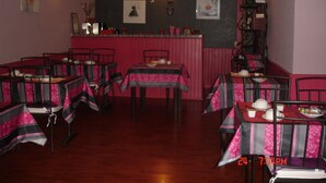 A restaurant with multiple tables and chairs, a bar area, and wall decorations. - Hotel La Marmotte (Niort)