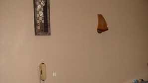 A hotel room with a bed, a bedside table, a lamp, a phone, and a painting on the wall. - Hotel La Marmotte (Niort)