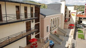 A hotel with multiple floors, outdoor seating areas, and a visible staircase. - Grand Palace (Akhaltsikhe)