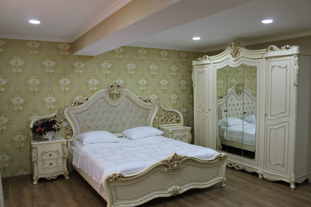 A bedroom with a large bed, a wardrobe, and a mirror.
