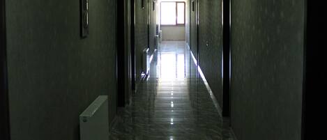 A long, narrow hallway with a shiny, reflective floor and doors on both sides.