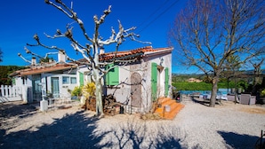 Une maison avec une allée en gravier, un petit patio avec une table et des chaises, et une vue sur la mer.
