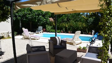 Een buitenzwembad, parasols bij het zwembad en ligstoelen
