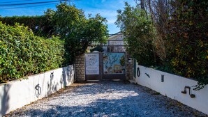 Un chemin de gravier mène à une porte agrémentée de panneaux d’information et d’une fresque murale.