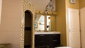Une chambre d’hôtel avec un mur recouvert de carreaux, un grand miroir, une porte blanche et un lit avec une couverture blanche.