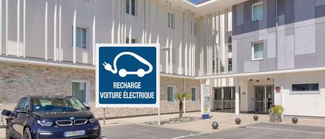 A modern building with a sign indicating electric vehicle charging.