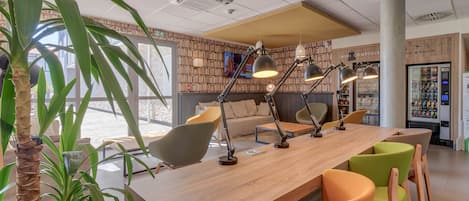 Un espace bar moderne avec un long comptoir en bois, de nombreuses chaises et des luminaires suspendus.