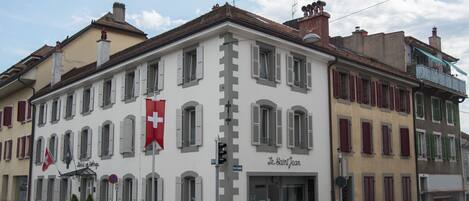 Un edificio con un letrero que dice "Le Saint Jean" y una bandera suiza.