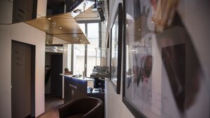 A modern hotel lobby with a reception desk, framed artwork on the walls, and a seating area with a brown armchair. - Hôtel de l'Ange (Nyon)