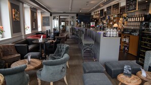 A bar area with seating, a bar counter, and a wine rack. - Hôtel de l'Ange (Nyon)