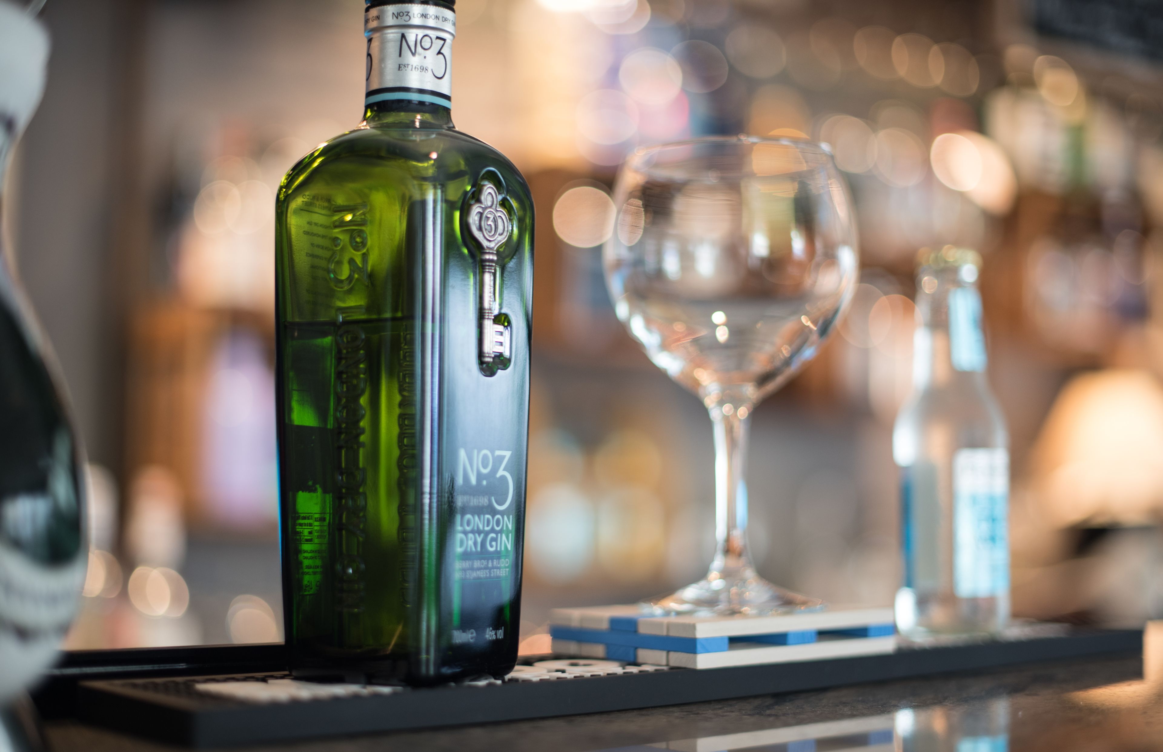 Una botella de ginebra London Dry No. 3 y un vaso sobre la barra.