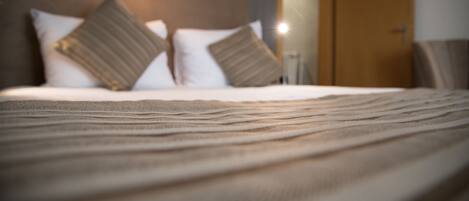 A bed with a striped blanket, two pillows, and a headboard with a light fixture.
