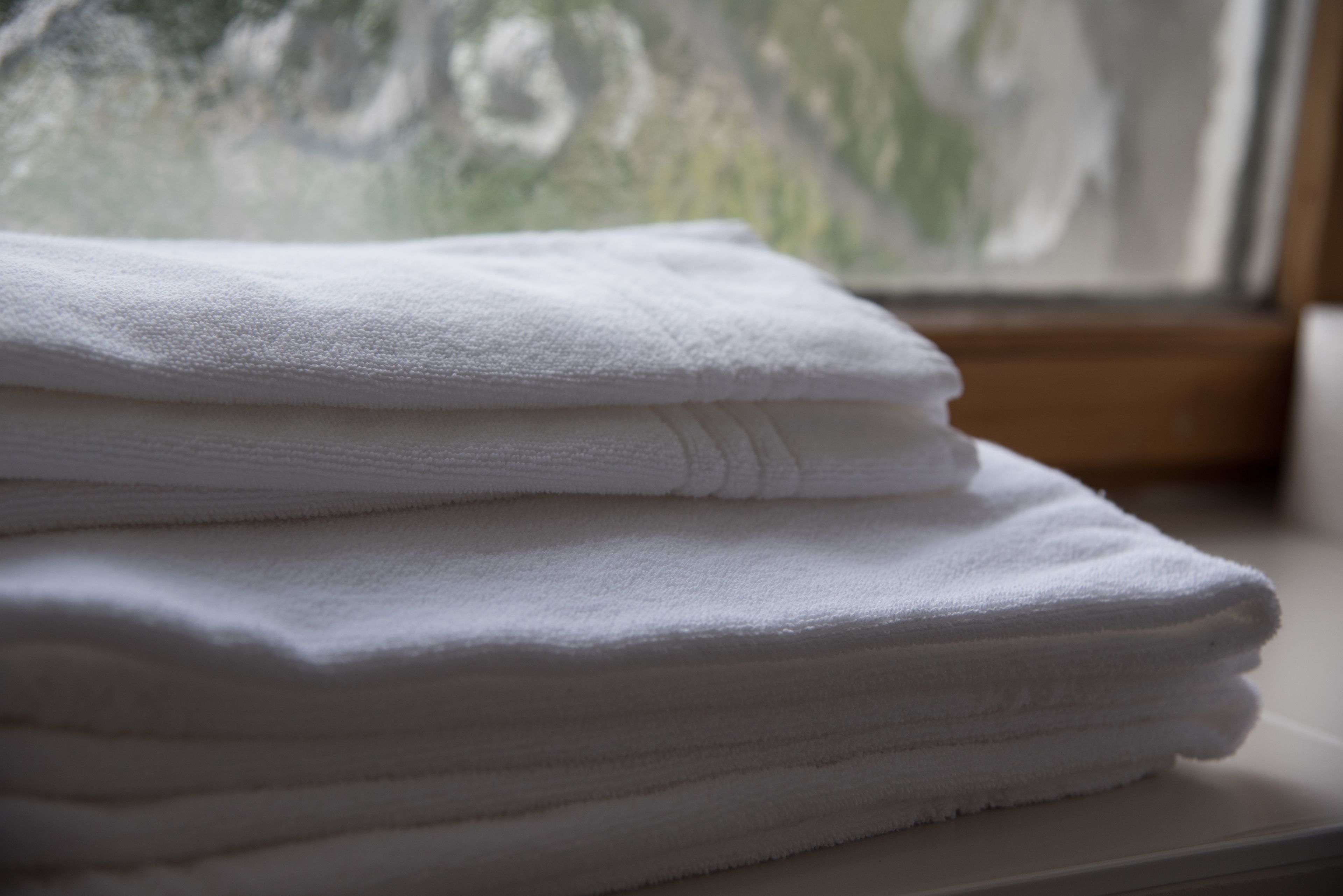 A stack of white towels on a white surface.