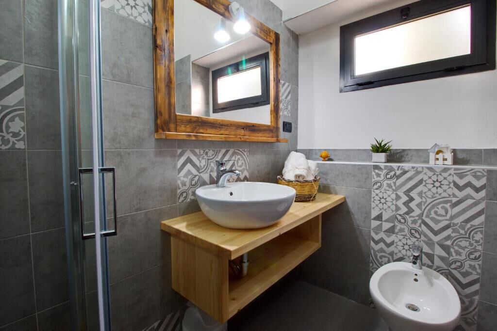 Un baño moderno con cabina de ducha de vidrio, tocador de madera con lavamanos blanco y un bidé.