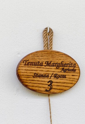 Een houten bord met gegraveerde tekst die een kamer nummer en naam aangeeft.