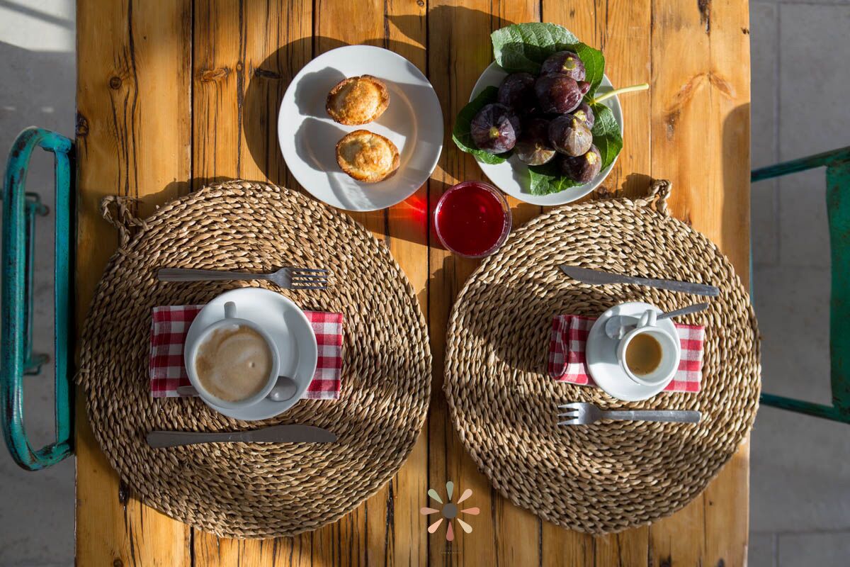 A wooden table with woven placemats, two plates of food, and two cups of coffee.
