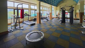 Un gimnasio con equipo de ejercicio, ventanas amplias y un techo con diseño.