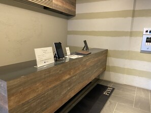 A reception desk with a wooden finish, a black phone, and a sign with text.