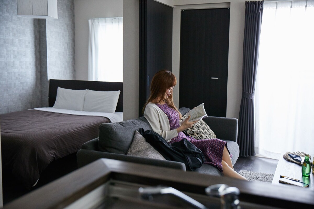 A modern hotel room with a bed, a sofa, and a coffee table.