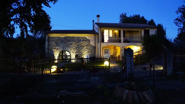 A two-story house with a stone facade, a balcony, and a gated entrance. - Molino Della Volta (Grosseto)