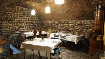 A restaurant with stone walls and wooden ceiling, featuring tables set for dining.