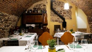 A restaurant with stone walls and wooden furniture, featuring tables set for dining with wine glasses and cutlery. - Molino Della Volta (Grosseto)