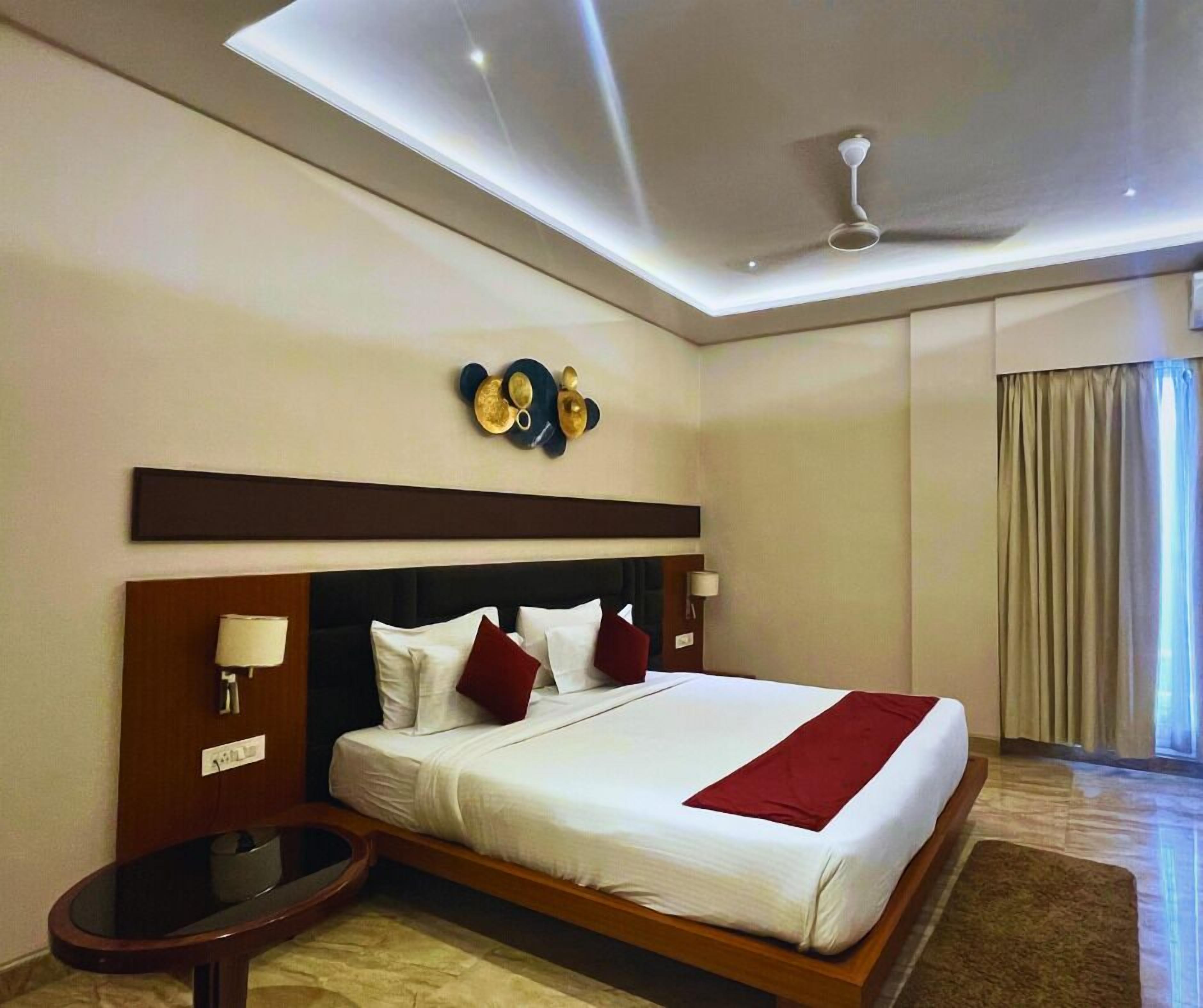 Una habitación de hotel moderna con una cama grande, un ventilador de techo y un adorno en la pared sobre la cama.