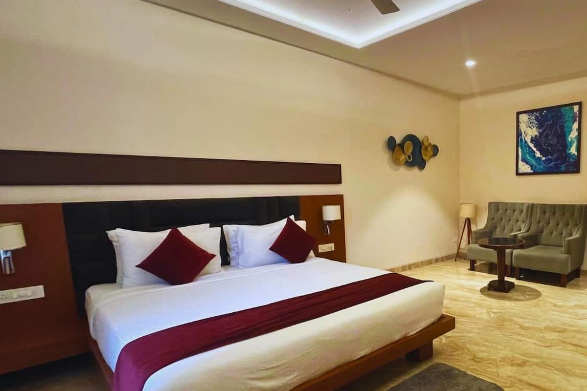 Una habitación de hotel con una cama grande, un sofá, una mesita y un cuadro en la pared.