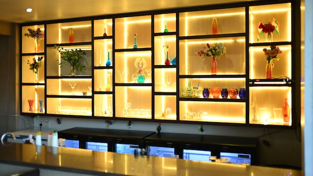 Zona de bar con estantes que exhiben diversas botellas y copas.
