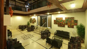 A spacious lobby with a high ceiling, multiple seating areas, and artwork on the walls. - Hotel Nandan (Guwahati)