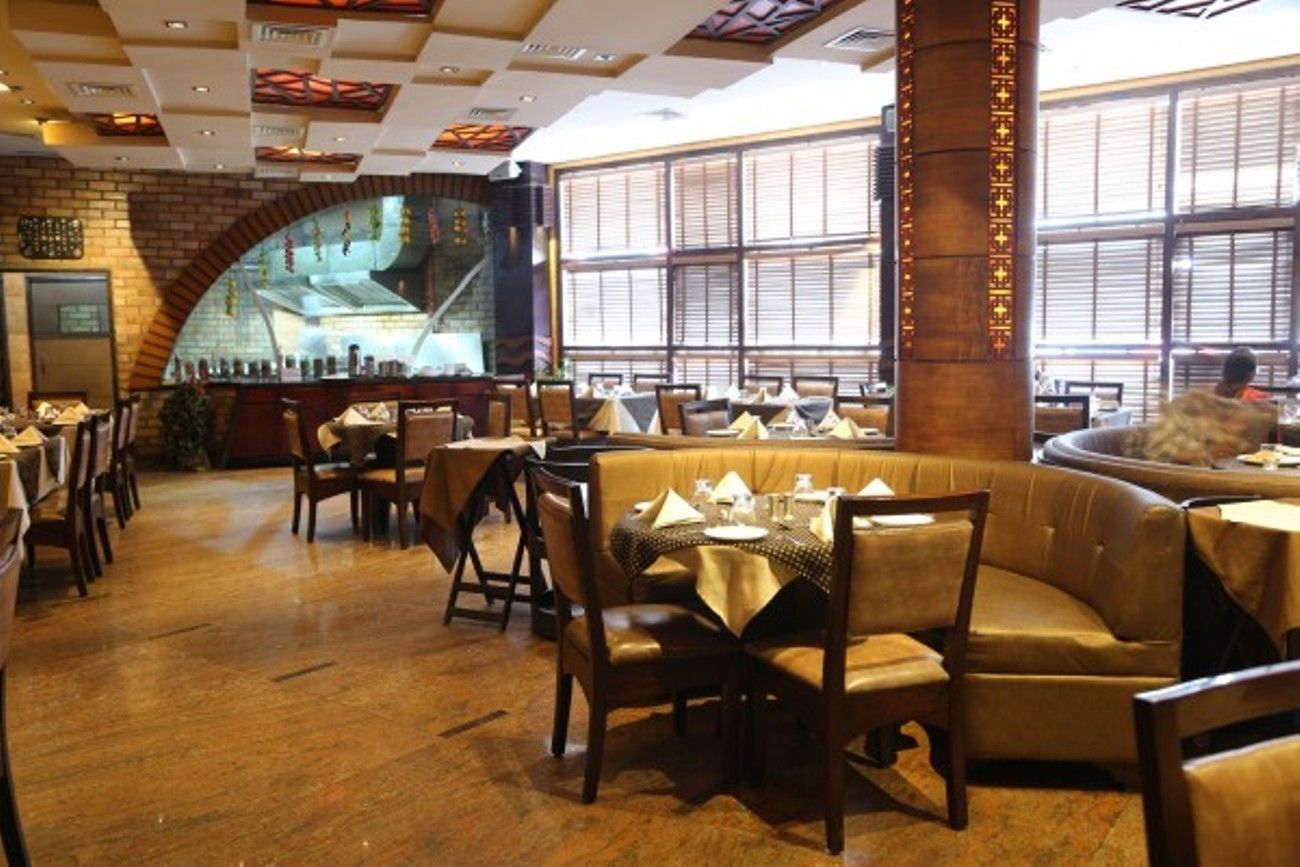 A restaurant with booths and tables, brick walls, and large windows.