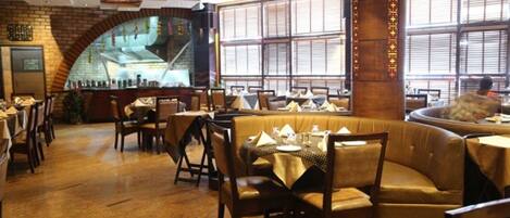 A restaurant with booths and tables, brick walls, and large windows.