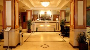 A hotel lobby with a reception desk, potted plants, and a chandelier. - Hotel Nandan (Guwahati)