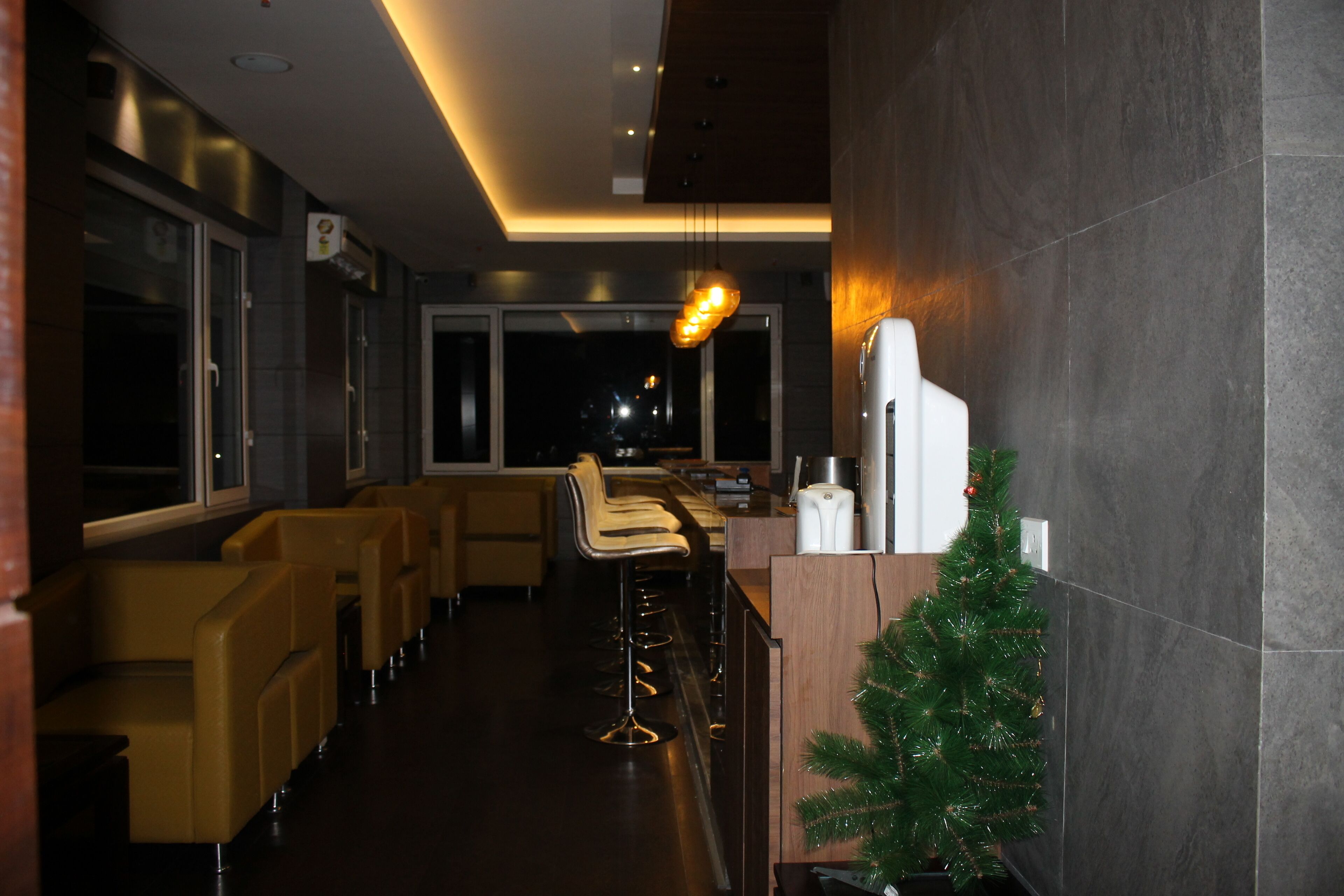 Un espace bar moderne avec des tabourets hauts, un petit sapin de Noël et un comptoir avec une machine à café.
