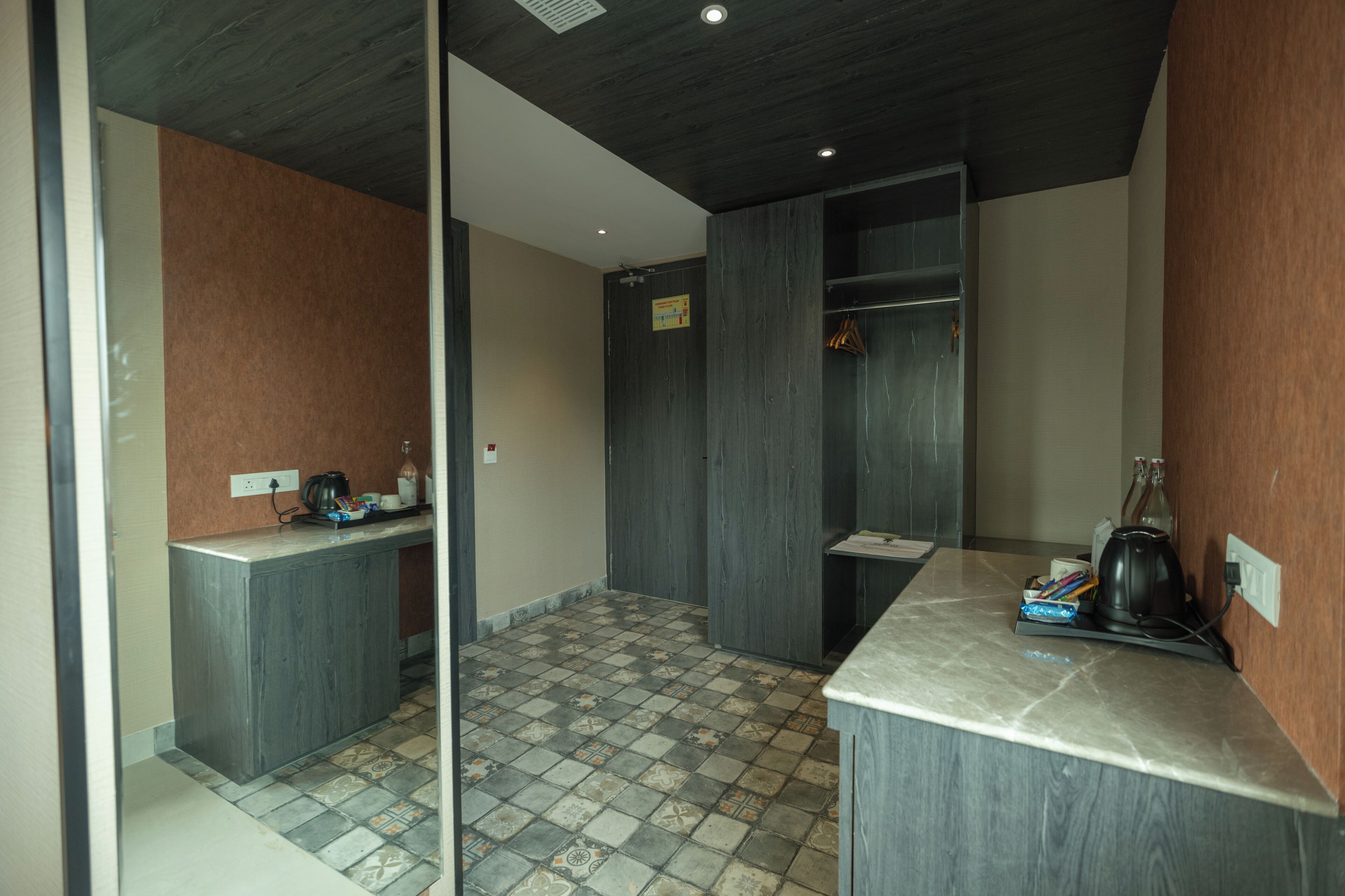 A modern kitchen with dark wood cabinets, a tiled floor, and a countertop with a kettle and a mug.