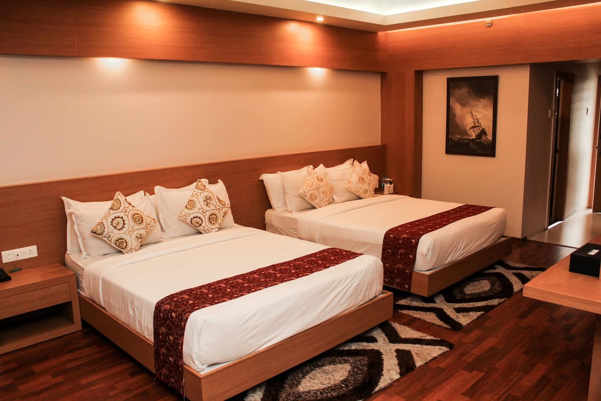 A hotel room with two beds, wooden headboards, a nightstand, a desk, and a painting on the wall.