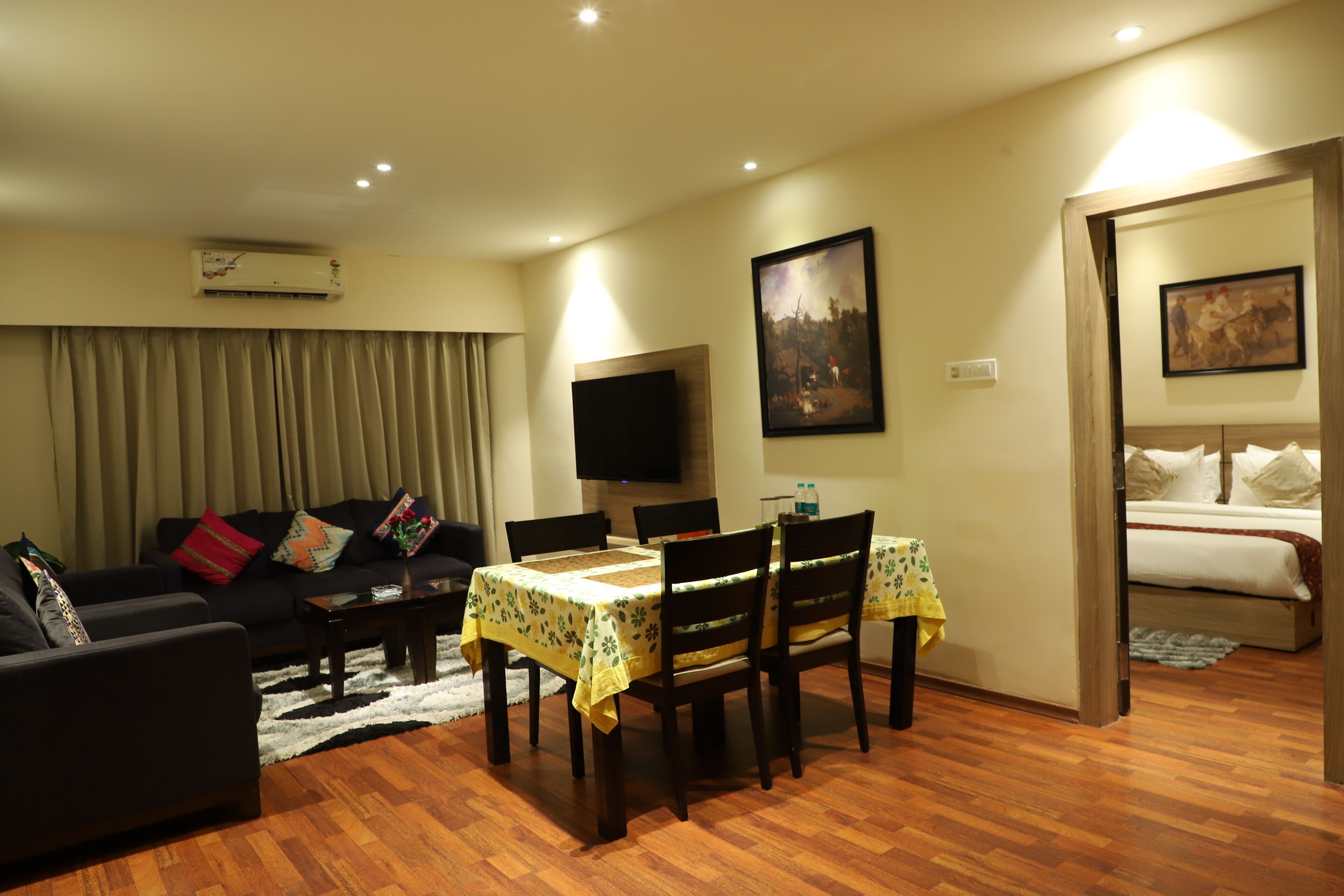 Un salon comprenant un canapé, une table à manger avec des chaises, un téléviseur à écran plat et un tableau accroché au mur.