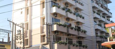 Un edificio de varios pisos con balcones, una entrada con reja y un coche estacionado.