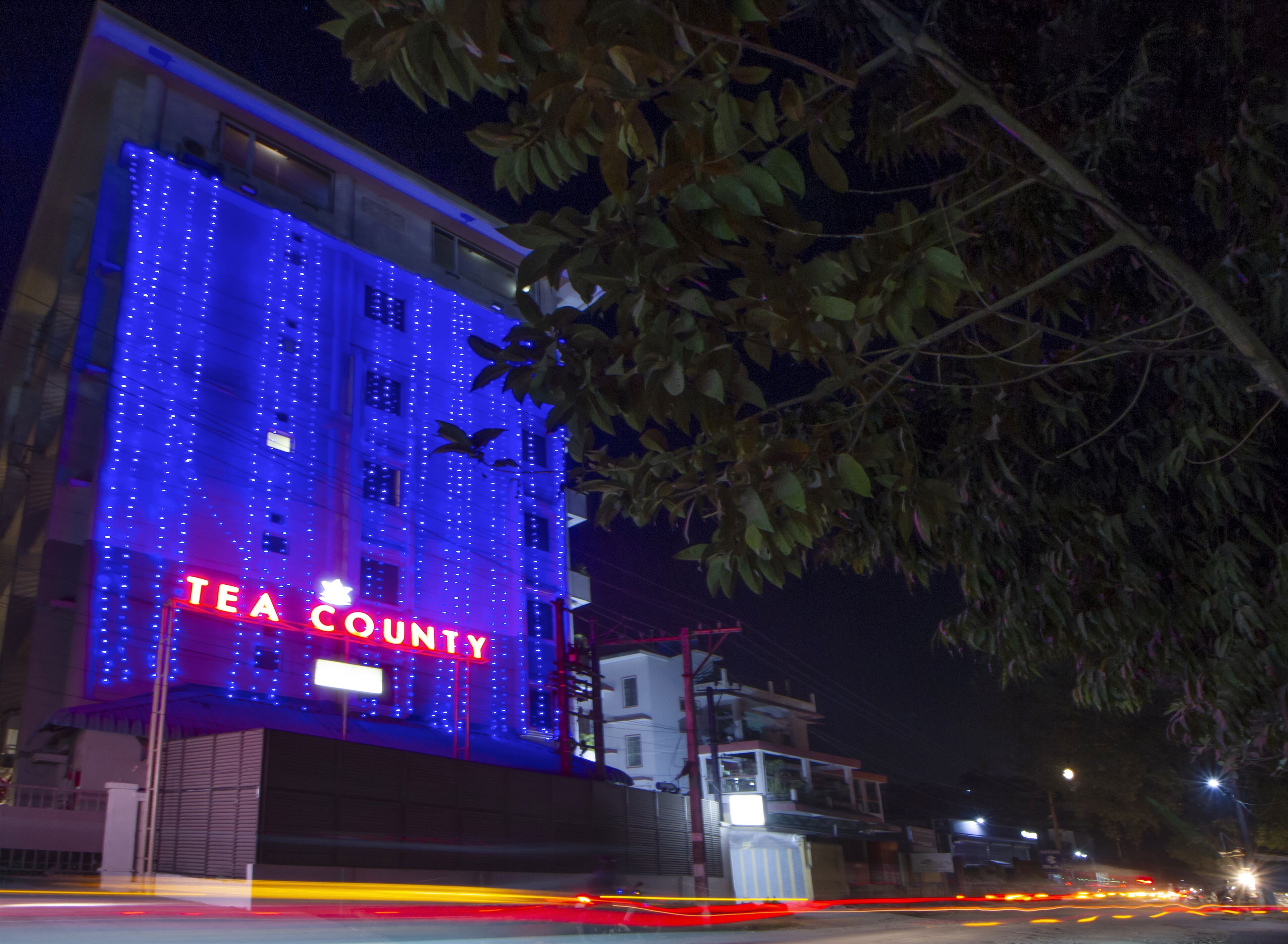 A building with a sign reading "TEA COUNTY" illuminated by blue lights.
