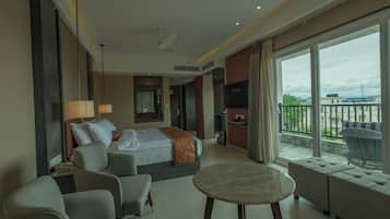 Una habitación de hotel con cama, sofá, mesa y balcón con vistas.