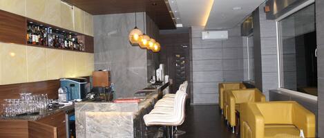 A modern bar area with a marble countertop, multiple bar stools, and a variety of bottles and glasses.