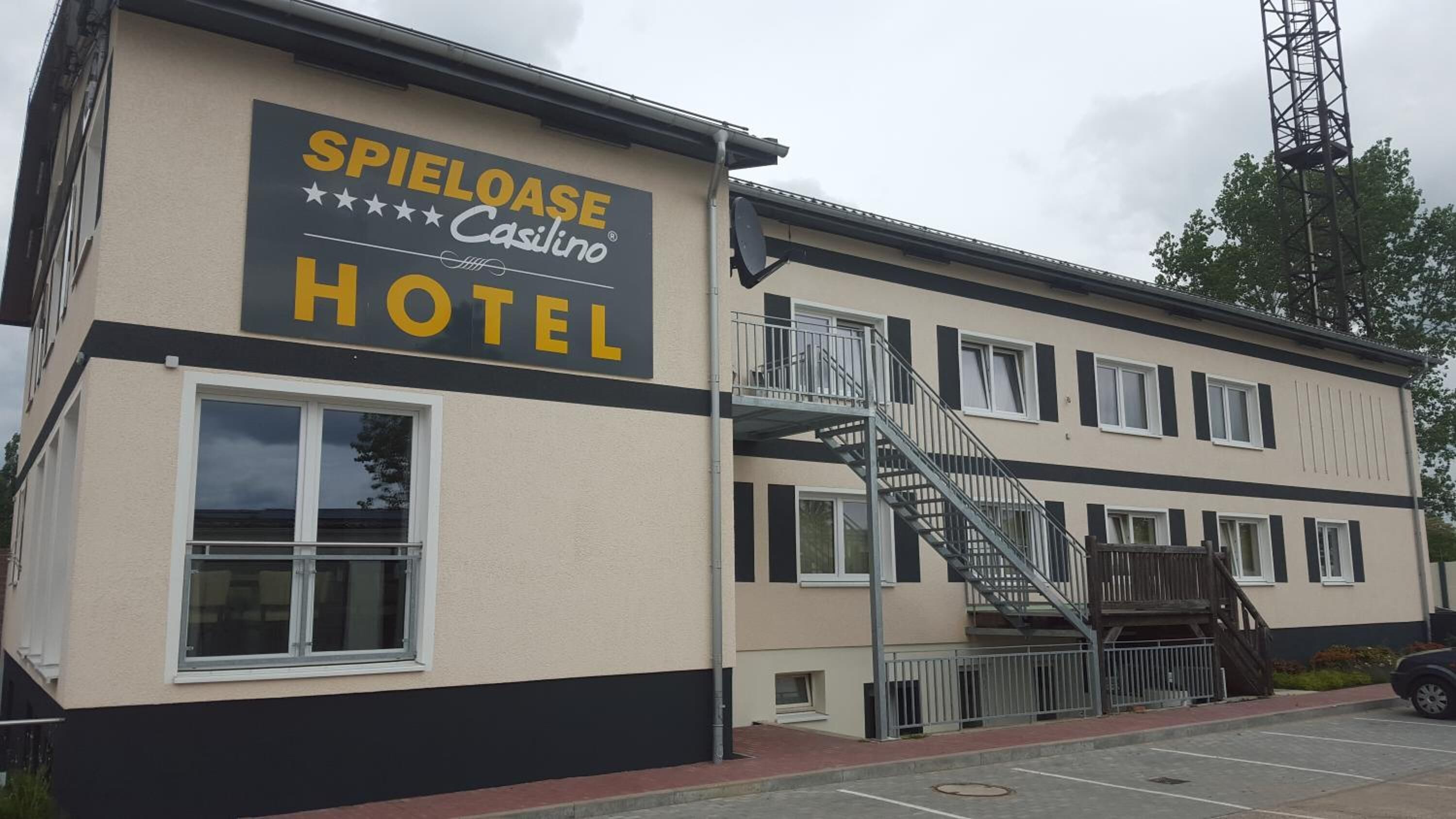 Ein Hotel namens SPIELOASE Casillero mit moderner Fassade, einer sichtbaren Treppe und einem Parkplatz.