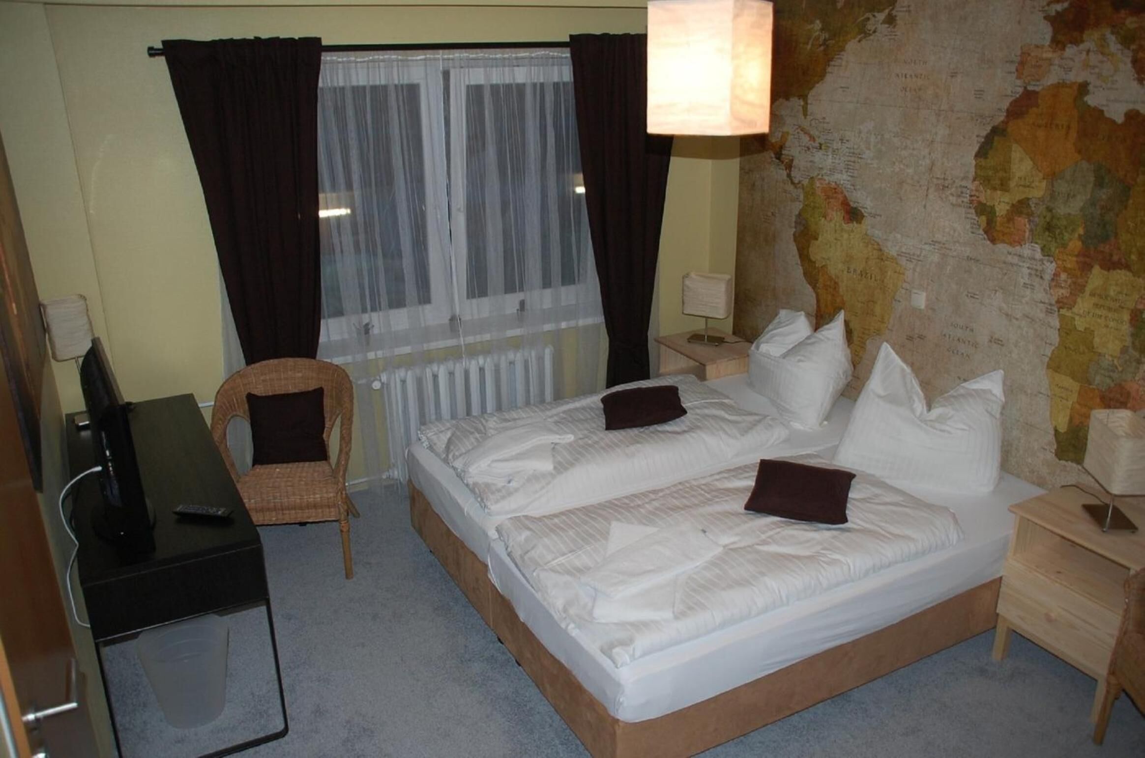Una habitación de hotel con una cama, una silla, un escritorio y un mapa en la pared.