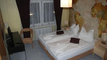 Una habitación de hotel con una cama, una silla, un escritorio y un mapa en la pared.