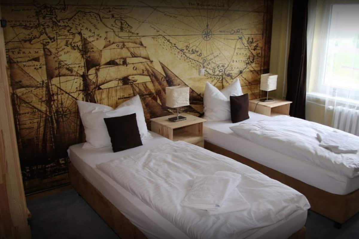 Ett hotellrum med två separata sängar, en stor karta på väggen och ett fönster med gardiner.